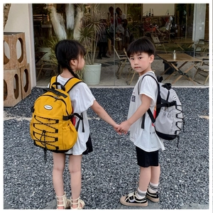 Outdoor back view of kids wearing lightweight yellow and grey canvas drawstring backpacks