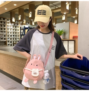 Pink cartoon rabbit crossbody canvas bag with plush pendant on a model in a store