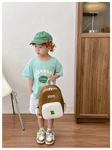 Detailed side view of a brown and white canvas toddler backpack held by a young boy