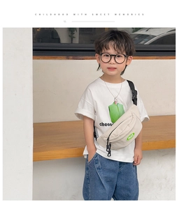 Close-up of kids cream canvas chest bag featuring a green PEACE label and nylon strap