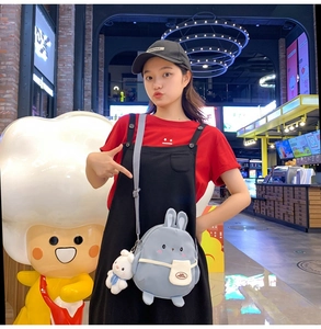 Close-up of light blue rabbit canvas bag with white pocket and cute doll keychain charm