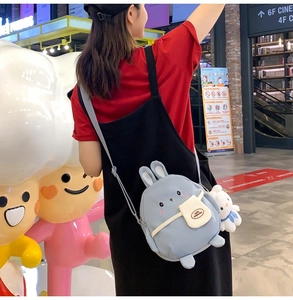 Close-up of light blue rabbit-shaped canvas crossbody bag with cute plush bunny charm
