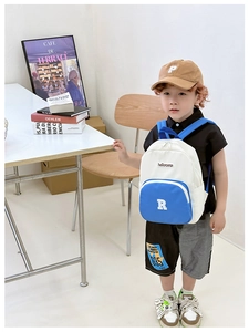 Detail of color-block canvas kids backpack with blue zipper pocket and R embroidery