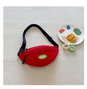 Close-up of red canvas kids waist bag with green PEACE embroidery and black strap