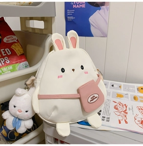 Detail of cute rabbit canvas crossbody bag with plush charm and pink ear accents
