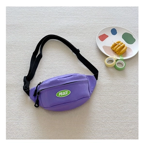 Detail view of purple canvas chest bag with green PEACE patch and black adjustable strap