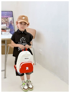 Detailed close-up of a child's canvas backpack with orange contrast and letter R branding