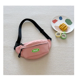 Detail of pink canvas chest bag with PEACE patch and adjustable black nylon strap