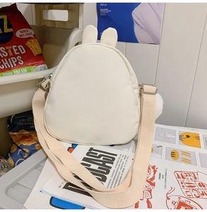 Detail of cute white rabbit-shaped crossbody bag with soft ears and canvas strap