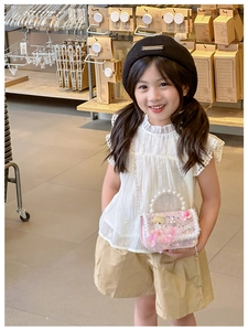 Pink kids lace purse with floral decor, pearls and a gold chain strap worn by a child