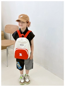 Detail of color-block canvas kids backpack featuring red front pocket and letter printing