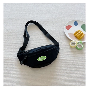 Close-up of black canvas kids chest bag with green PEACE embroidery and adjustable strap