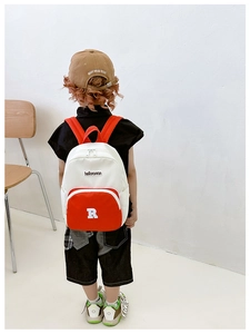 Rear view of child wearing contrast color canvas backpack with letter R patch