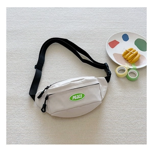 Detail of off-white canvas chest bag with green PEACE patch and black adjustable strap
