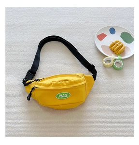 Detailed view of yellow canvas kids chest bag with PEACE patch and adjustable black strap