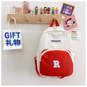Close-up of color-block canvas backpack with large letter R patch and front zip pocket