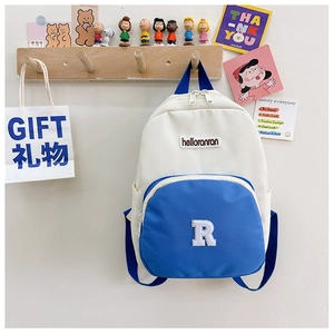 Detail of color-block canvas kids backpack showing blue pocket with R logo and zipper