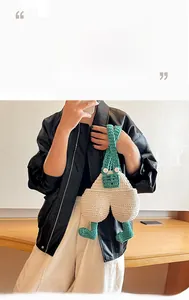 Detail of handmade crochet phone bag shaped like cute green and white overall pants