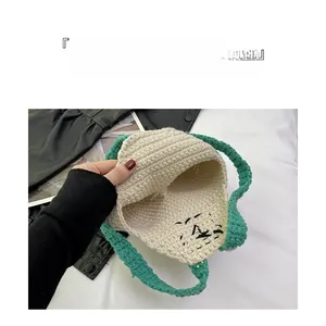 Detail view of the open interior space and green handles of the handmade crochet bag