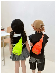 Detail of neon green and bright orange kids chest bags featuring stylish letter prints
