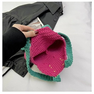 Detailed knit texture of a pink and green handmade crochet bag on dark leather