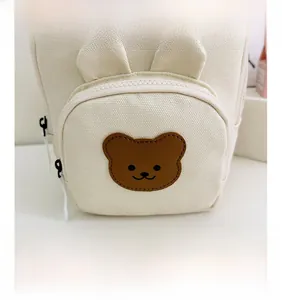 Détail de l'écusson ours en cuir et des coutures sur un sac à dos pour enfant en toile