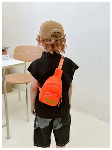 Detail view of orange canvas crossbody bag with adjustable strap for kids on a model