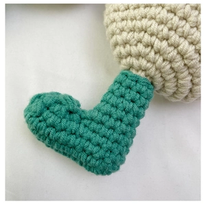 Close-up of handmade crochet texture and teal stitching on a cream knit crossbody bag