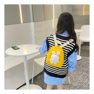 Close-up of yellow canvas backpack for kids featuring a 3D plush bunny doll and straps