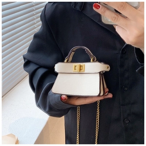 Dettaglio di una mini borsa a trapezio in pelle bianca con chiusura a scatto dorata e catena