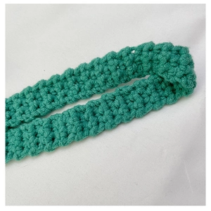 Close-up of vibrant green hand-crocheted fabric showing detailed textured stitch patterns