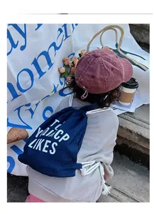 Navy canvas drawstring backpack with white lettering and vintage pink cotton baseball cap
