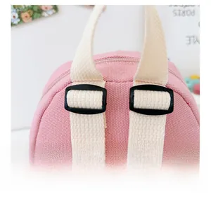 Close-up of adjustable shoulder strap and plastic buckle on pink canvas backpack