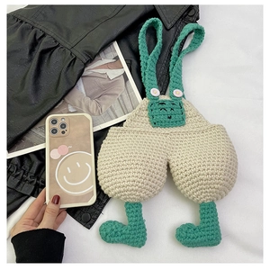 Detail of handmade crochet phone bag with overall suspender design and green buttons