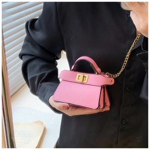 Dettaglio mini borsa rosa con chiusura a scatto dorata e catena in metallo su fondo scuro