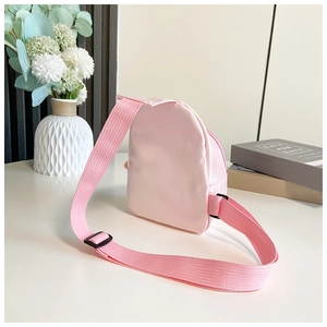 Detail of adjustable shoulder strap and zipper closure on pink mini crossbody bag