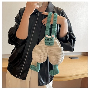 Detail of handmade knit overalls crossbody bag with mint green straps and 3D leg accents