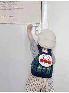 Detail of Anpanman character embroidery on a blue denim kids' backpack with green plaid pattern