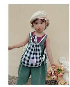 Close-up of kids black and white checkered canvas drawstring bag with a pink logo tag