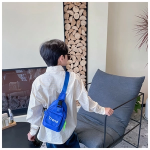 Detail view of a blue canvas chest bag for kids with adjustable strap and Trend logo