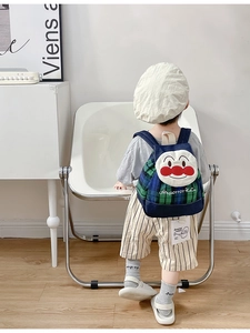 Detailed close-up of a blue and green plaid kids backpack with a cute mascot patch