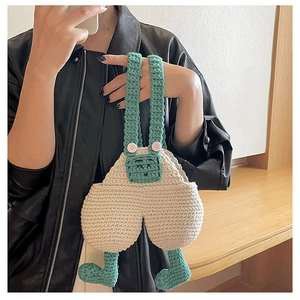 Detail of handmade crochet crossbody bag with overalls design and cute knitted legs
