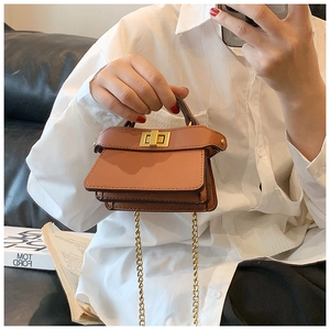 Dettaglio mini borsa in pelle caramello con chiusura a scatto dorata e tracolla a catena