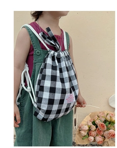 Detail of a child wearing a black and white checkered canvas drawstring backpack