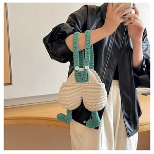 Detailed view of handmade crochet overall-shaped bag worn by model in a mirror selfie