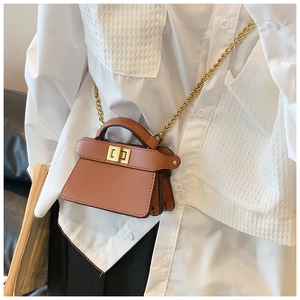 Dettaglio mini borsa a tracolla marrone con chiusura a scatto dorata e tracolla a catena
