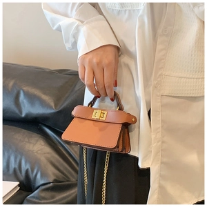 Dettaglio mini borsa a tracolla marrone caramello con chiusura dorata e catenella