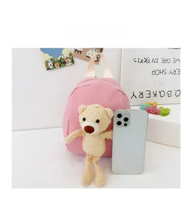 Size comparison of a pink mini canvas backpack for kids with a cute plush bear