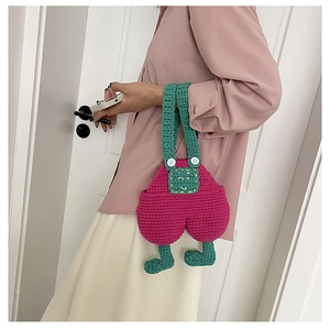 Detail of handmade crochet phone bag in overall shape with smiling face embroidery