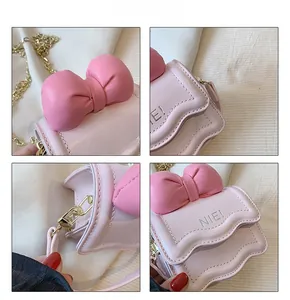 Détails du mini sac bandoulière rose avec grand nœud, texte NIE! et chaîne dorée